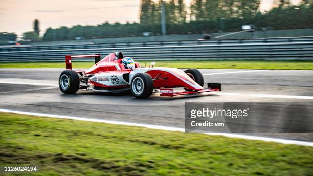 panning shot of a red formula car - grand prix motor racing stock pictures, royalty-free photos & images