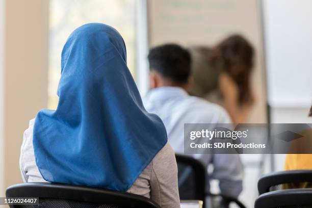 bakifrån av kvinna som bär hijab sitter i klassrummet - huvudduk bildbanksfoton och bilder
