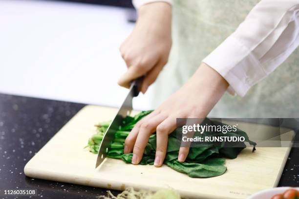 woman cutting vegetables in kitchen - coupant photos et images de collection