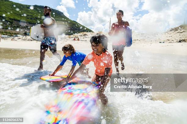 family running and splashing into sea together with body boards - beach holiday stock-fotos und bilder