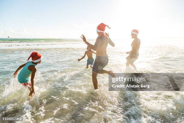 family enjoying christmas together on the beach - christmas summer stockfoto's en -beelden