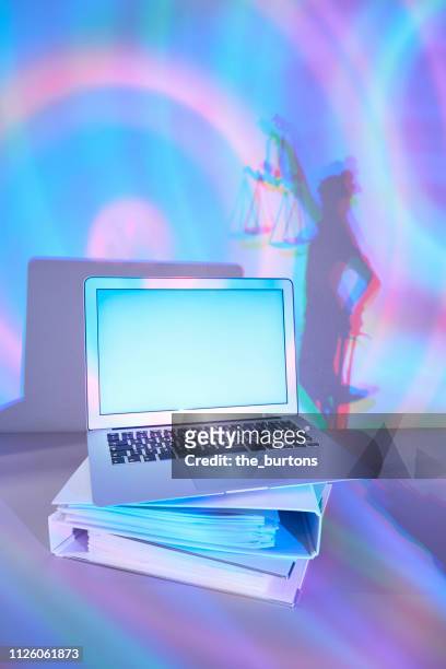 laptop on stacked file folders and shadow of lady justice, conceptual image of cyber crime - lady justice technology stock pictures, royalty-free photos & images