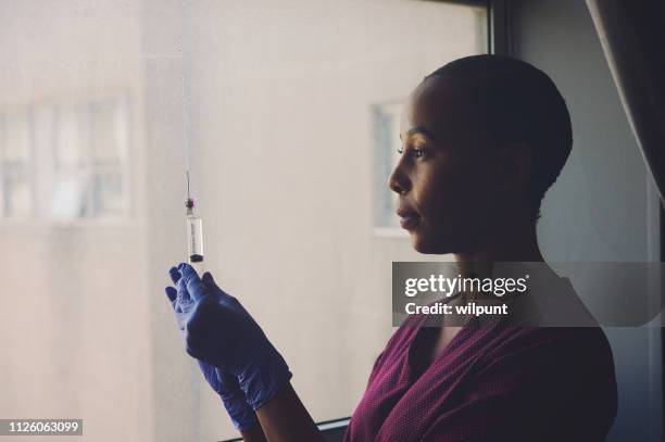 portrait of a female nurse testing a syringe in the hospital side view toned - vaccine confidence stock pictures, royalty-free photos & images