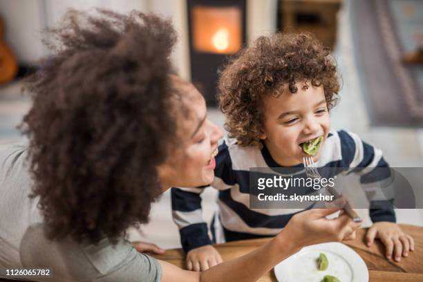 非裔美國人的母親用獼猴桃餵養她快樂的兒子。 - kiwi fruit 個照片及圖片檔