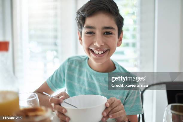 ritratto di ragazzo sorridente che sta facendo colazione a casa - boy eating cereal foto e immagini stock