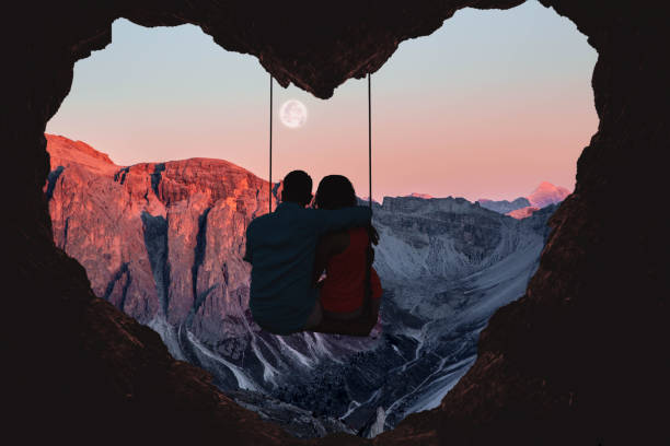 couple on swing contemplating the mountains in a romantic view with heart shape. - couple destination stock pictures, royalty-free photos & images