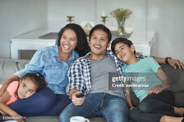 happy parents watching tv with children at home - la four stock pictures, royalty-free photos & images