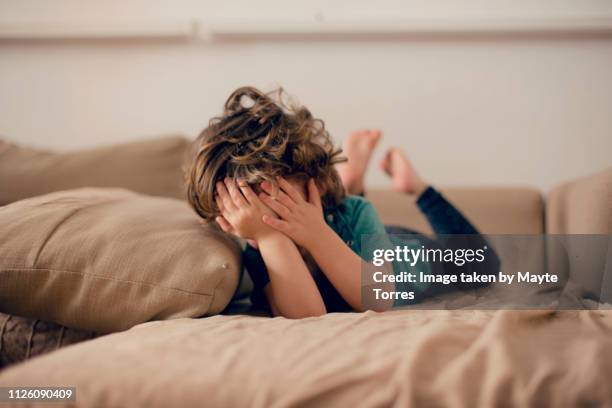 toddler laying in sofa covering his face - tímido imagens e fotografias de stock