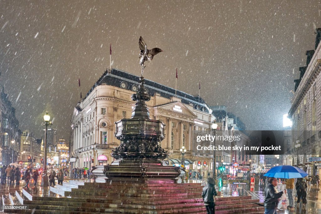 Piccadilly circus and the statue known as Eros as it is snowing.