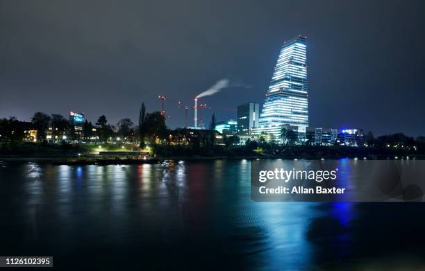 skyline of the 'roche tower' on riverside of the river rhine illuminated at night - skyline basel fotografías e imágenes de stock