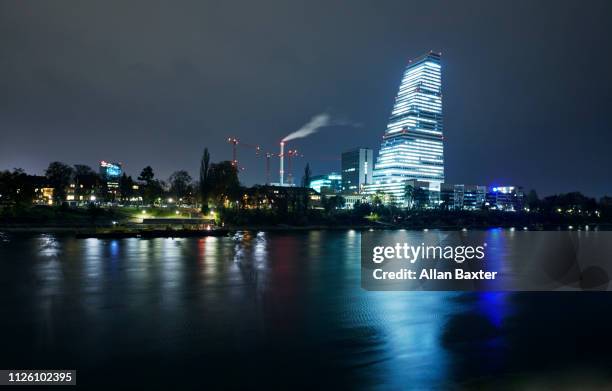 skyline of the 'roche tower' on riverside of the river rhine illuminated at night - basel port stock pictures, royalty-free photos & images