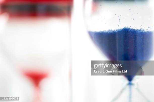 politics concept - red and blue hourglasses filling up with sand - article 50 of the treaty on european union stock pictures, royalty-free photos & images