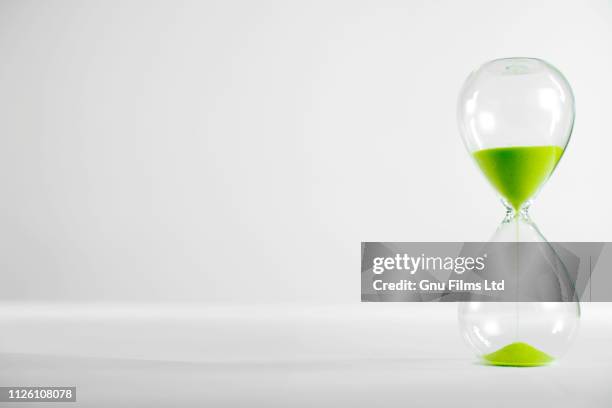 environement concept - a green hourglass filling up with sand - biologische uhr stock-fotos und bilder