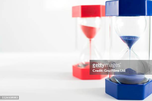 politics concept - red and blue hourglasses filling up with sand - conservative party uk stock pictures, royalty-free photos & images