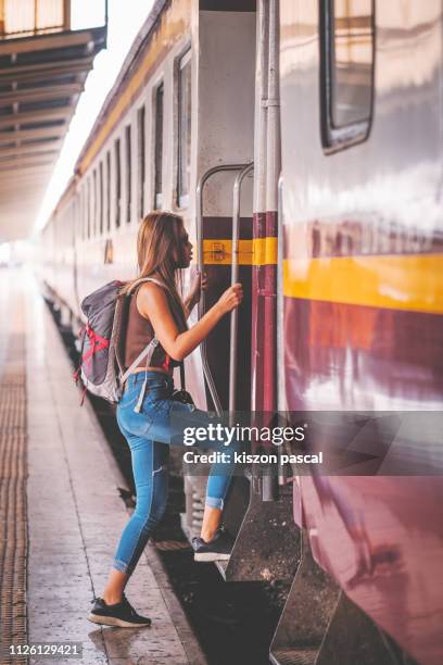 woman backpacker gets on the train in railway station . - vacation train stock pictures, royalty-free photos & images