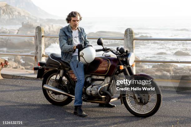 man adjusting helmut on vintage motorcycle - vintage jeans stock pictures, royalty-free photos & images