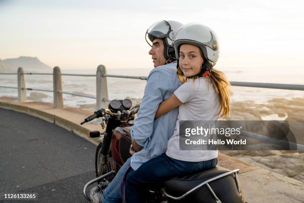 happy daughter ready to ride on back of motorcycle with dad - mare moto foto e immagini stock