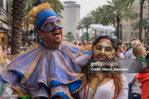 a smiling couple wearing costumes in the street during the mardi gras celebration at new orleans carnival, louisiana, usa . - festival of beads street carnival stock pictures, royalty-free photos & images