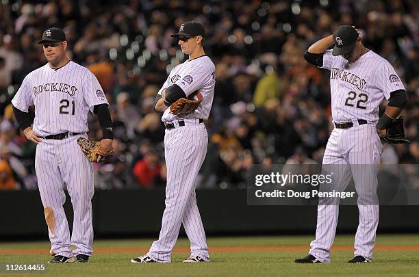 Ty Wigginton, Troy Tulowitzki and Jose Lopez of the Colorado Rockies await a pitching change against the San Francisco Giants in the eighth inning at...