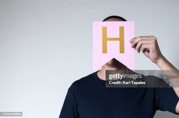 a young man holding a capital letter "h" - obscured face stock pictures, royalty-free photos & images