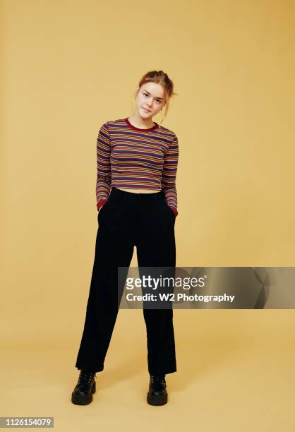 portrait of young woman standing on a yellow background. - ganzkörperansicht stock-fotos und bilder