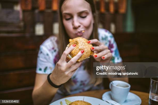 vrouw delicious hamburger eten - hand uitsteken stockfoto's en -beelden