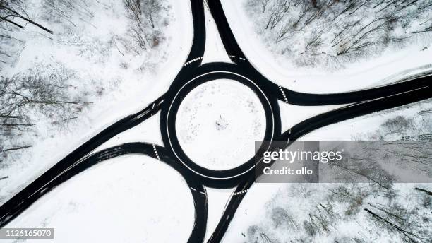 carrefour giratoire et la route qui traverse la forêt hivernale - route sapin neige photos et images de collection
