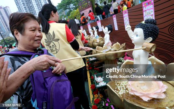 Believer cleanses a buddha statue with water to pray for good luck and health. Buddha's birthday carnival takes place at Victoria Park, Causeway Bay....