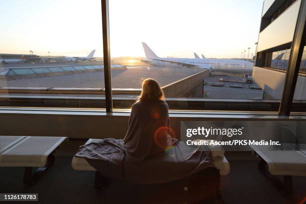 woman relaxes in airport lobby, planes in distance - narita stock-fotos und bilder