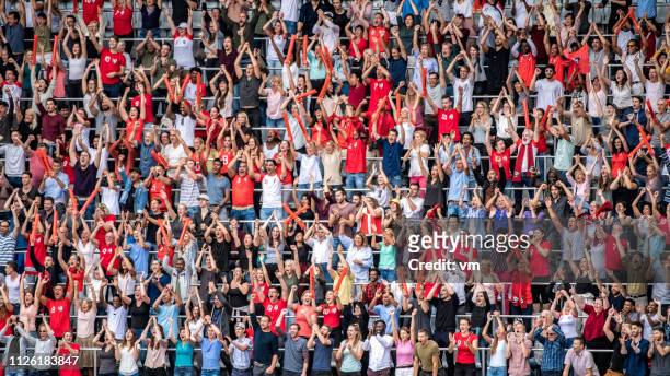 gli appassionati di sport in maglia rossa tifano per le gradinate dello stadio - avvenimento sportivo foto e immagini stock
