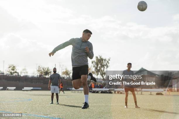 young man heading a soccer ball - faire une tête photos et images de collection