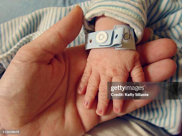 wrinkled newborn hand with hospital bracelet - hospital nursery ストックフォトと画像