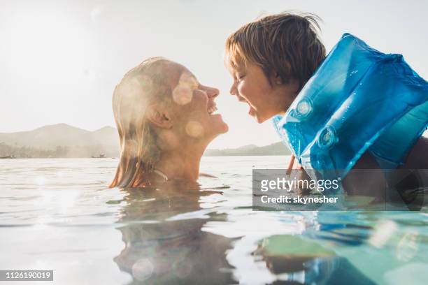 glückliche mutter und sohn spaß beim schwimmen im meer in den sommerferien. - swim safety stock-fotos und bilder
