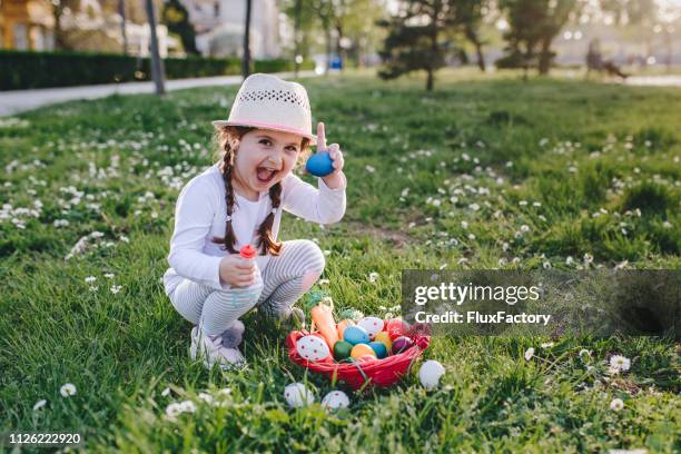 portrait of a little four year old girl holding an egg she found during an easter egg hunt - easter egg hunt outside stock pictures, royalty-free photos & images