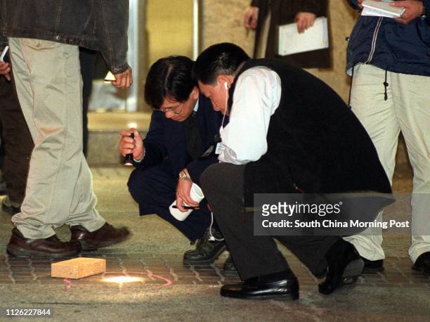 Police officers look at a piece of evidence for the shooting in a $1 million robbery outside the Tsuen Kam Centre Hong Kong Jockey Club off-course...