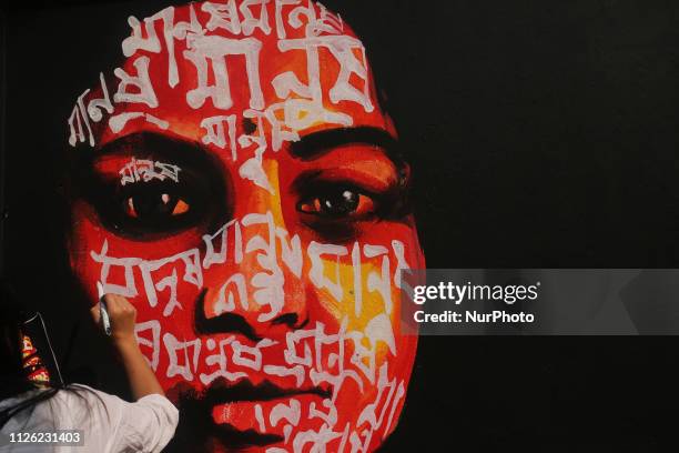 Student of the Fine Art Institute of Dhaka University painting on the wall ahead of International Mother Language Day around the central Shaheed...