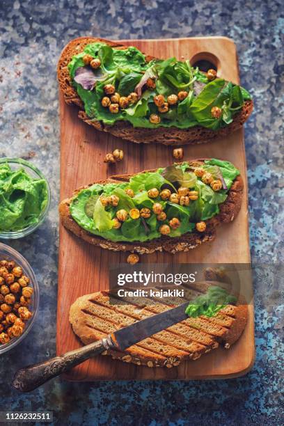 avocado toast topped with hummus, salad and crispy roasted chickpeas - avacado oil stock pictures, royalty-free photos & images