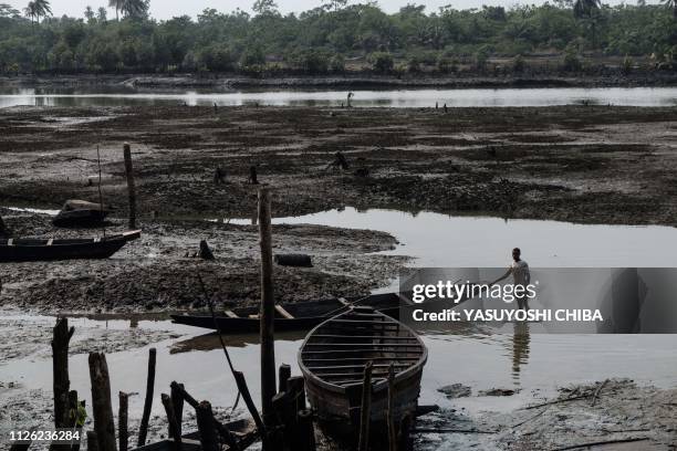 Fisherman pushes his boat during low tide on oily mud in the river at Ogoniland's village of K-Dere, near Bodo, which is part of the Niger Delta...