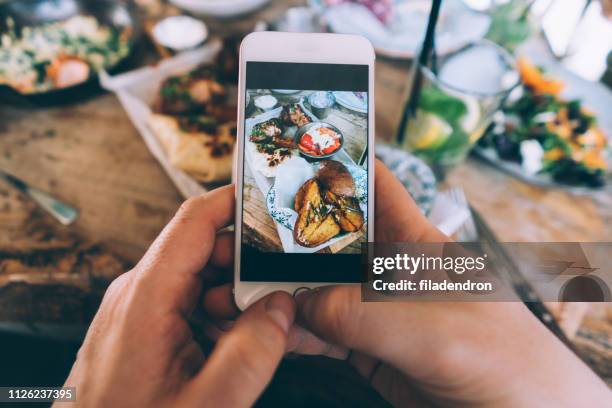 essen teilen - taking photo with phone stock-fotos und bilder