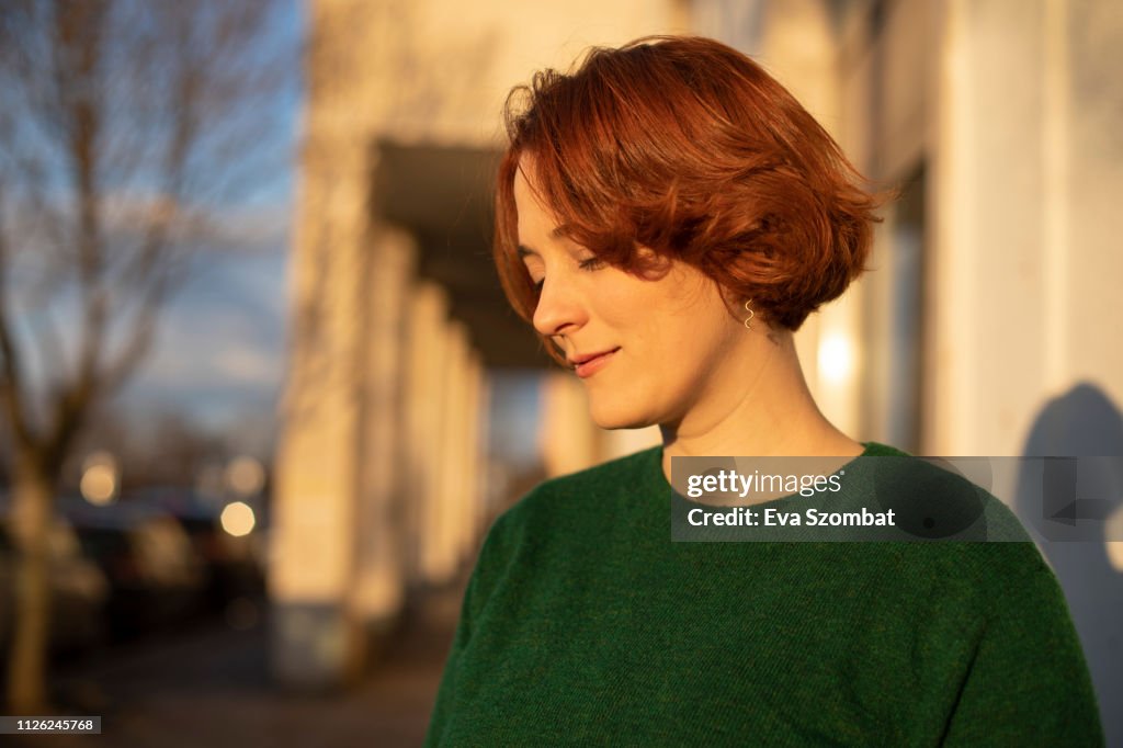 Redheaded woman standing on the street during sunset