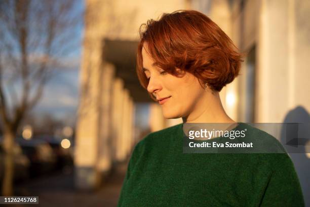 Redheaded woman standing on the street during sunset