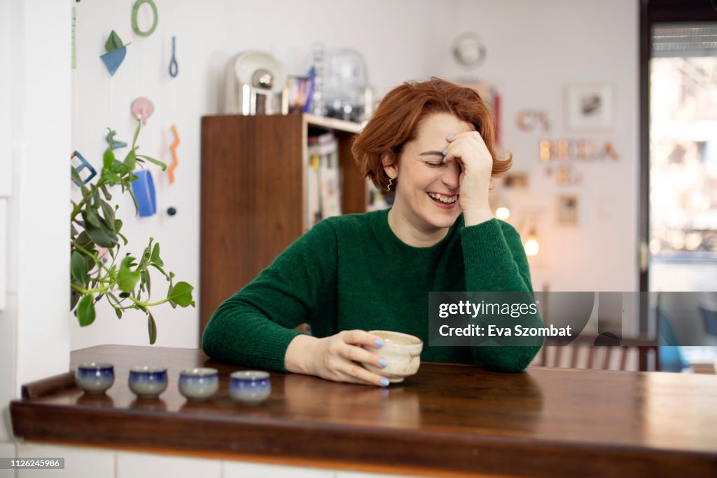 Woman laughing at home drinking tea