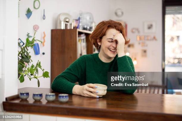 woman laughing at home drinking tea
