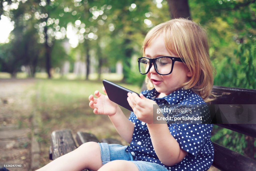 Little nerd boy with eyeglasses using smart phone