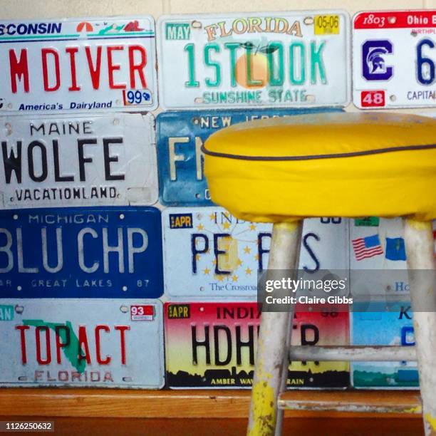 yellow stool against license plates on wall - florida license plate stock pictures, royalty-free photos & images