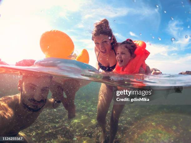 madre e padre insegnano alle figlie a nuotare - half underwater foto e immagini stock