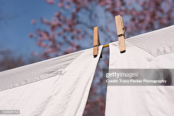 freshly laundered linen dries in spring sunshine. - washing line stock pictures, royalty-free photos & images