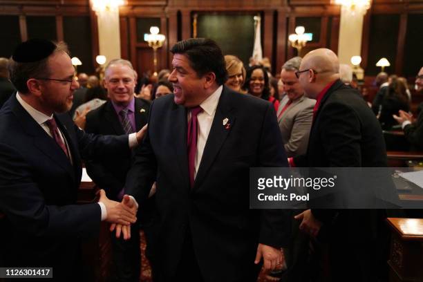 Illinois Gov. J.B. Pritzker is congratulated by lawmakers after delivering his first budget address to a joint session of the llinois House and...