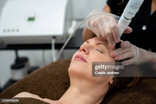 woman at the spa getting a facial laser treatment - laser face stock pictures, royalty-free photos & images