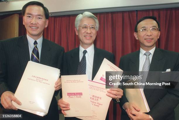 Bernard Chan, Yeung Ka-sing and Vincent Cheng Hoi-chuen show copies of the interim report released by a government-appointed taskforce's interim...